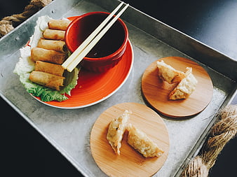 Asian spring rolls and dumplings on metal tray with dipping sauce