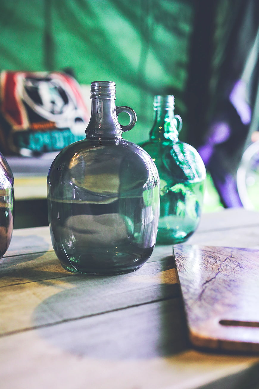 Vintage green glass demijohn bottles on rustic wooden table