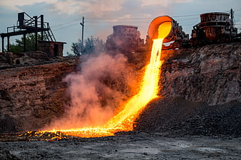 Molten metal pouring from industrial furnace at steel mill