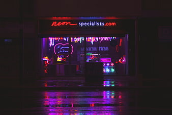 Neon shop window reflecting on wet street at night