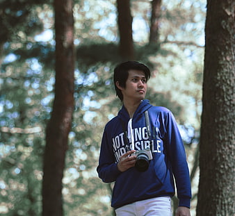 Young man with camera standing in forest