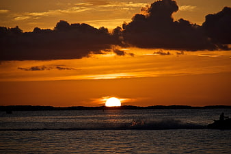 Dramatic Orange Sunset Over Ocean with Silhouette Clouds