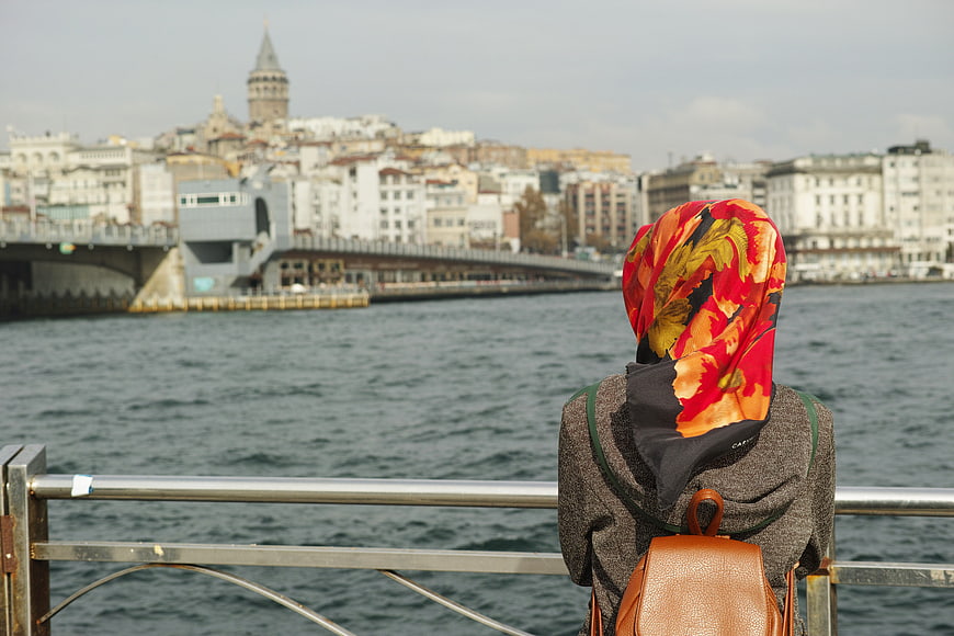 Woman in colorful hijab overlooking Istanbul waterfront and Galata Tower
