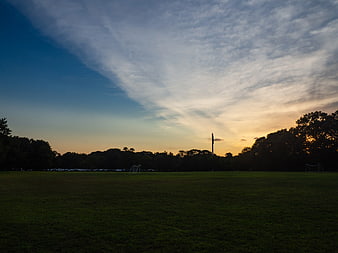 Sunset over a grassy park field with dramatic clouds