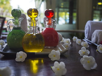Colorful Spa Oils and White Flowers on Wooden Table