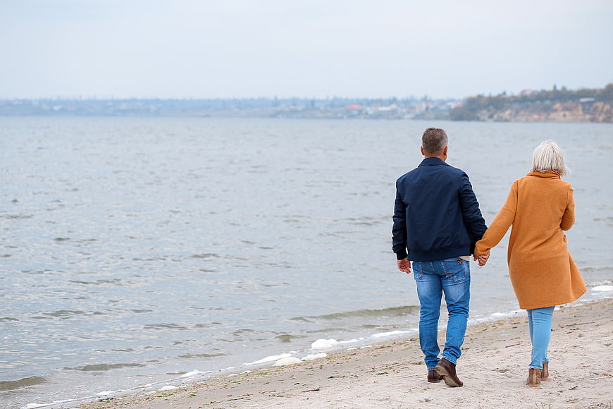 Senior Couple Walking Hand in Hand on Beach Shore