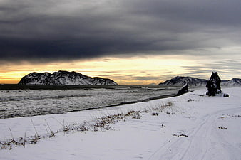 Dramatic Winter Seascape with Snowy Beach and Dark Clouds