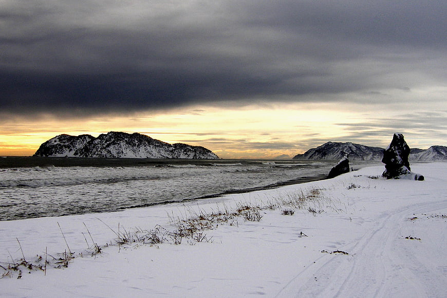 Dramatic Winter Seascape with Snowy Beach and Dark Clouds