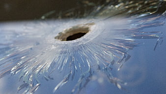 Close-up of shattered glass with central impact hole and radial cracks