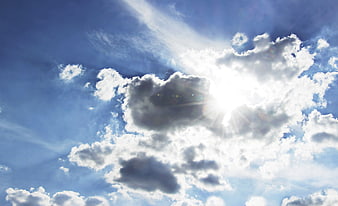 Bright Sunlight Breaking Through White Clouds In Blue Sky