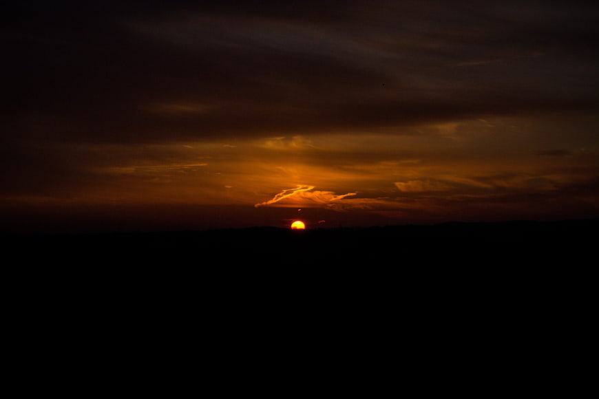 Dramatic orange sunset over dark silhouette landscape