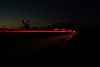 Long Exposure Red Taillight Trails on Dark Road with Windmill