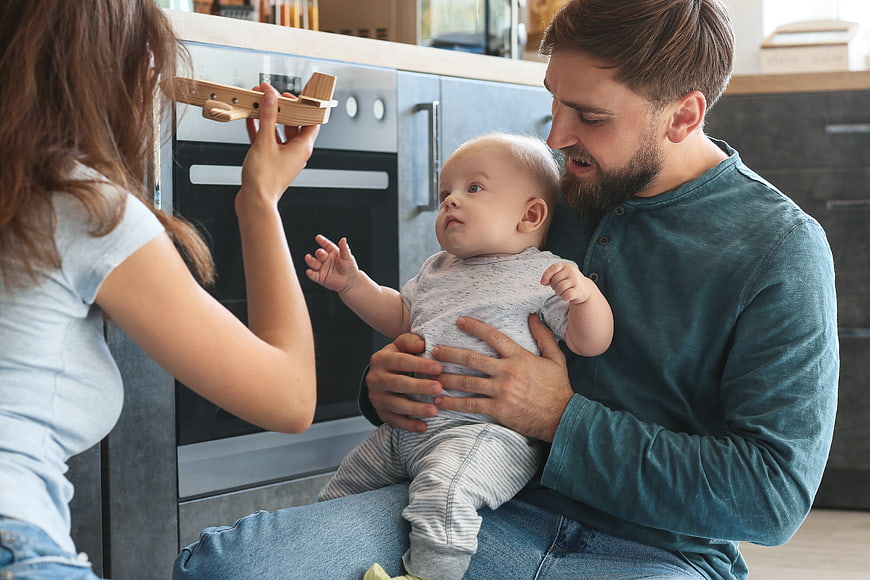 Young Family Playing with Wooden Toy Airplane in Kitchen