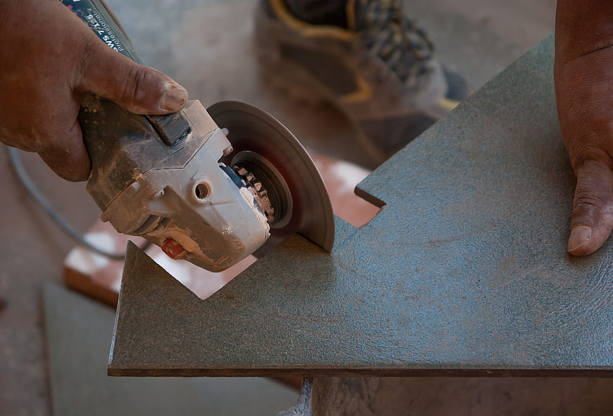 Close-up of worker using angle grinder to cut floor tile