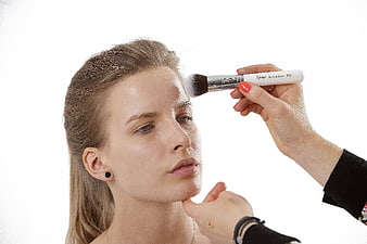 Professional Makeup Artist Applying Powder To Woman's Face
