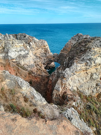 Dramatic coastal cliffs with natural rock arch overlooking blue ocean
