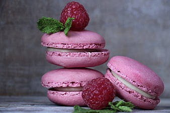 Stack of pink raspberry macarons with fresh berries and mint