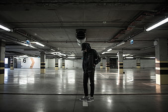 Man in Hoodie Standing Alone in Empty Parking Garage