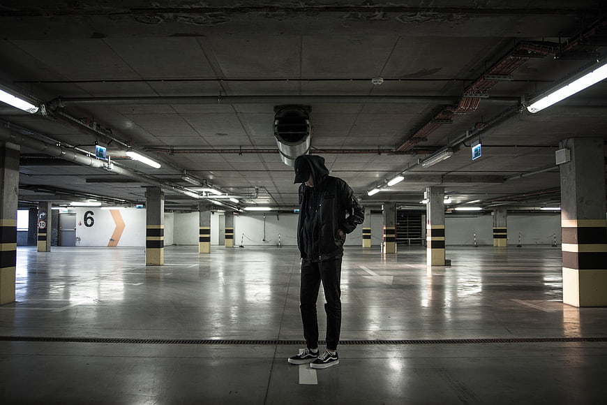 Man in Hoodie Standing Alone in Empty Parking Garage