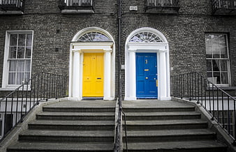 Symmetrical yellow and blue doors on grey brick building