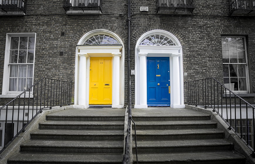 Symmetrical yellow and blue doors on grey brick building