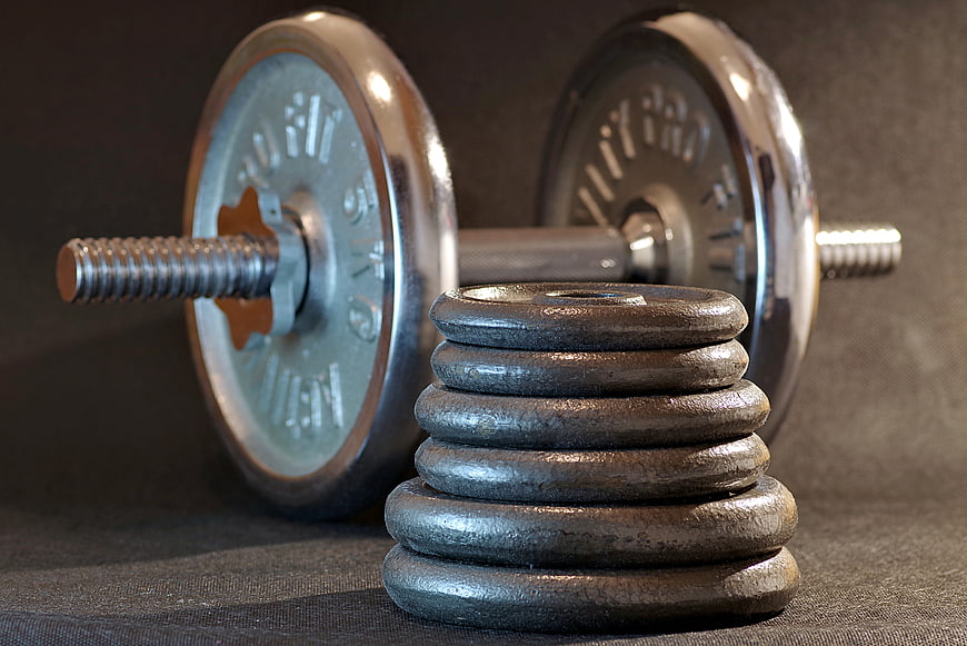 Stack of weight plates with barbell in background