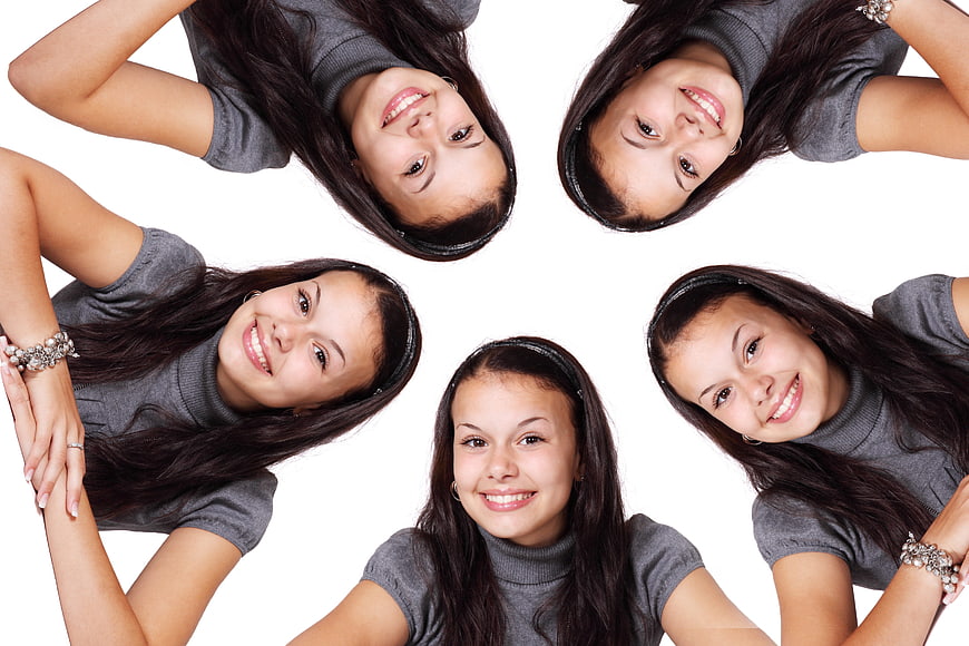 Five smiling young women in gray turtlenecks arranged in a circle