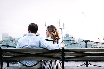 Couple sitting on bench overlooking harbor