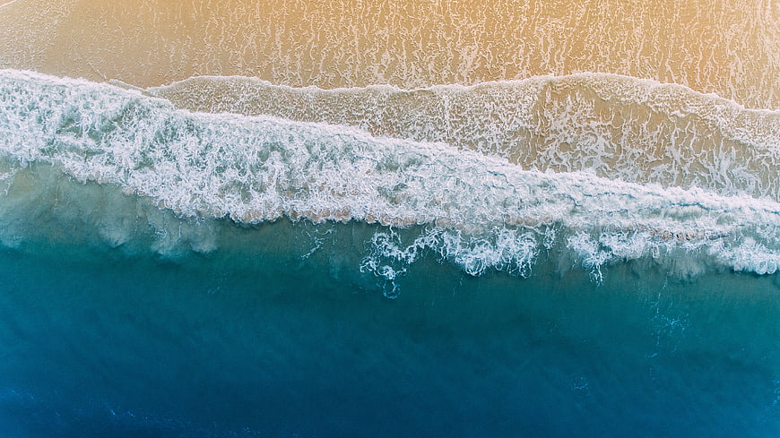 Aerial View of Ocean Waves Crashing on Sandy Beach
