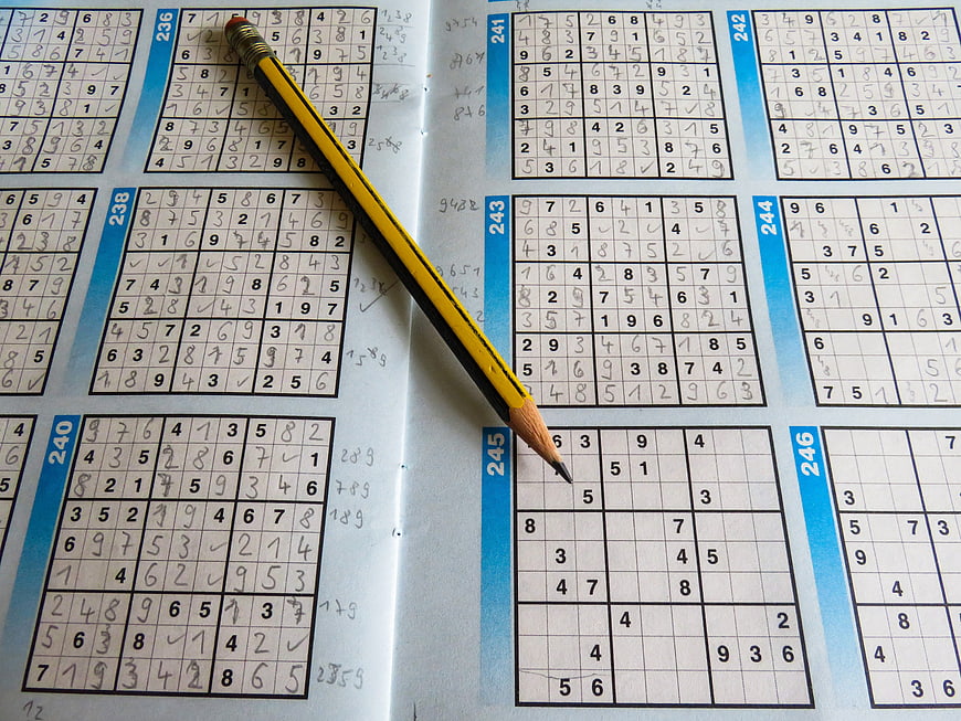 Yellow pencil on open sudoku puzzle book page
