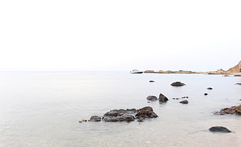 Serene coastal landscape with rocks, calm sea, and distant boat
