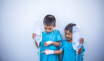 Two young boys in hospital gowns holding IV bags
