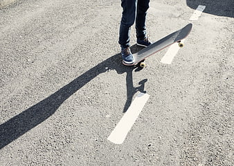Skateboarder Feet on Asphalt Road with Long Shadow