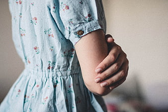 Close-up of woman's hand holding arm in floral dress