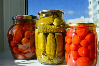 Jars of pickled cucumbers and tomatoes on a windowsill