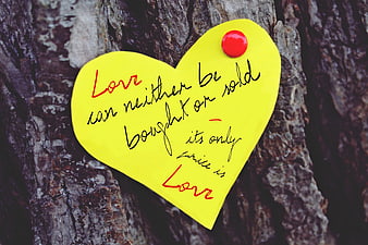 Yellow heart note with love quote pinned to tree bark