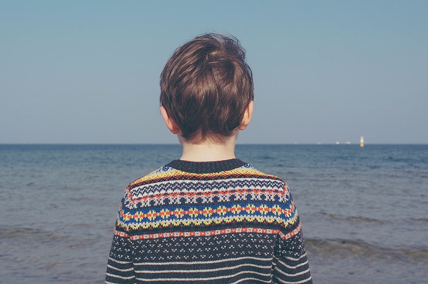 Boy in Patterned Sweater Looking Out at the Ocean