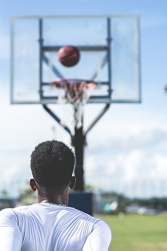 Basketball player shooting ball at hoop outdoors