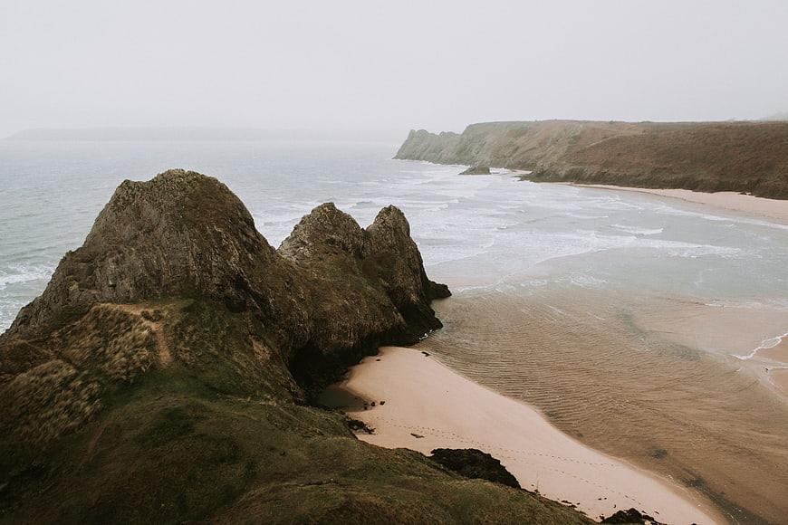 Misty coastal landscape with rocky cliffs and sandy beach