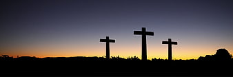 Silhouette of three crosses on a hill at sunset
