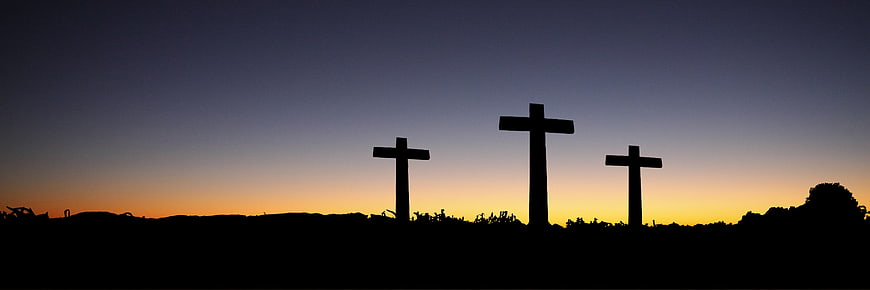 Silhouette of three crosses on a hill at sunset