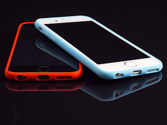 Two smartphones with colorful cases on reflective black surface
