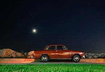 Vintage Red Car Parked Under Moonlit Night Sky