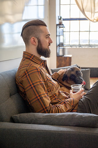 Relaxed man with beard sitting on couch petting dog