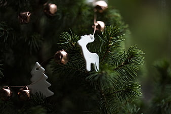 Close-up of white ceramic reindeer and tree ornaments on a Christmas tree