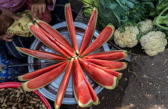 Sliced watermelon arranged in a flower pattern on a metal tray