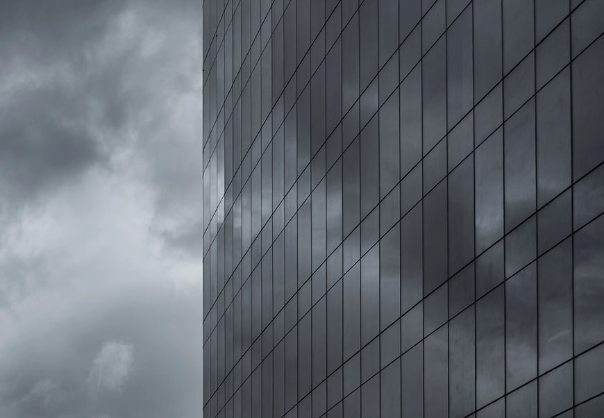 Modern Glass Building Facade Reflecting Stormy Clouds