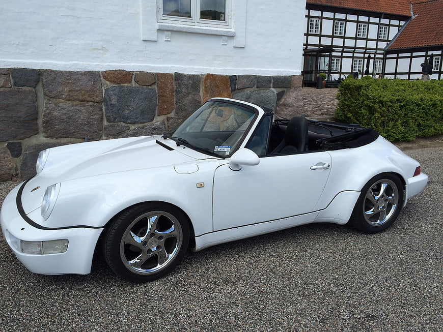 White Porsche 911 Speedster parked in front of a traditional European half-timbered house