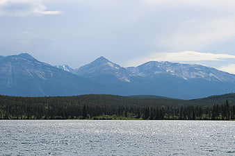 Scenic view of snow-capped mountains and forest across a lake