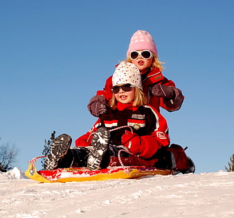 Two Girls Sledding Down Snowy Hill in Winter